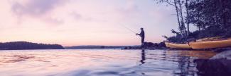 A man fishing against a purple sunset